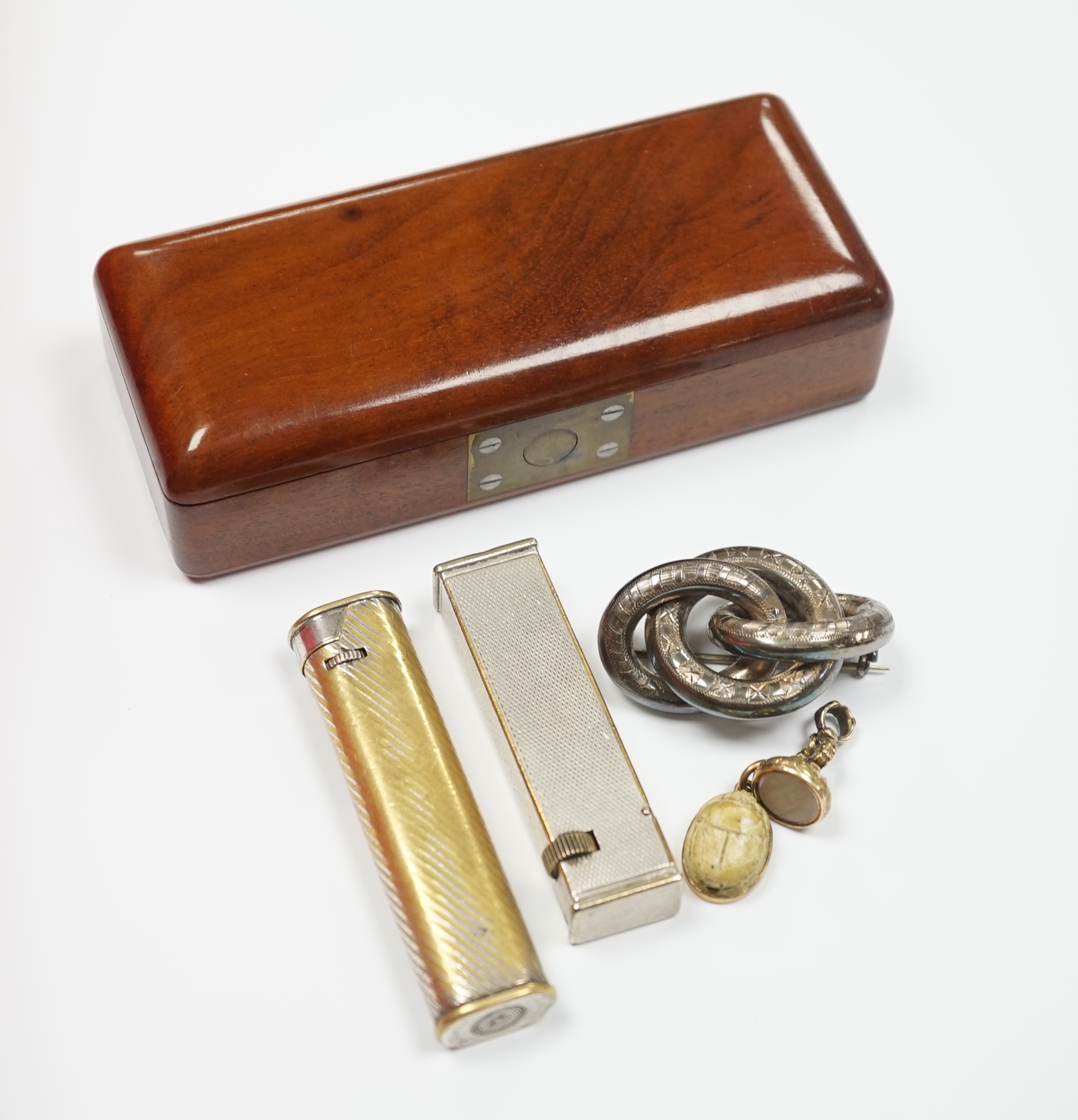 Two Dunhill lighters, largest 72mm, a yellow metal mounted scarab pendant, a gold plated and white carnelian set fob seal, the matrix carved with thistle and the phrase 'Dinna Tell', an engraved white metal knot brooch a